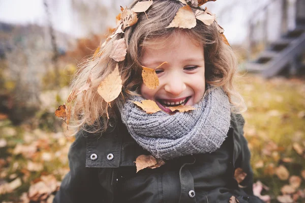 Glückliches Kind, das im Herbst mit Blättern spielt — Stockfoto