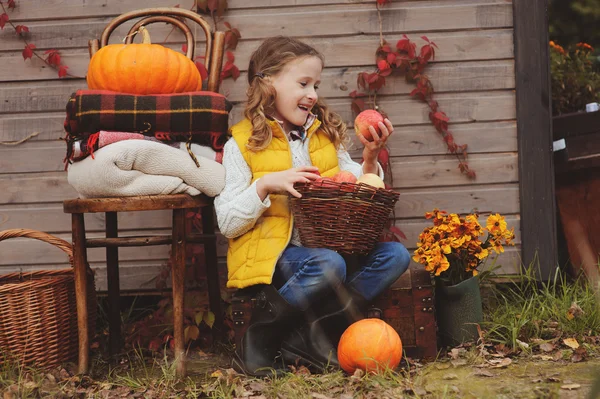 Šťastné dítě dívka výdeje čerstvá jablka na farmě. Země koncept bydlení, útulné sezónní dekorace na pozadí — Stock fotografie