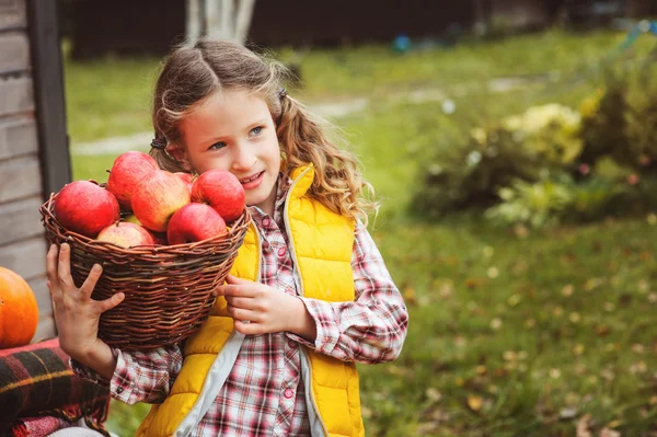 Šťastné dítě dívka výdeje čerstvá jablka na farmě. Země koncept bydlení, útulné sezónní dekorace na pozadí — Stock fotografie