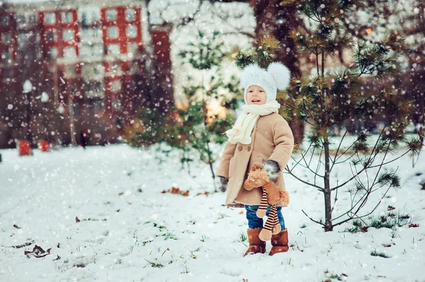 Aranyos baba lány élvezi téli séta a havas park, meleg kalapot és kabátot visel — Stock Fotó