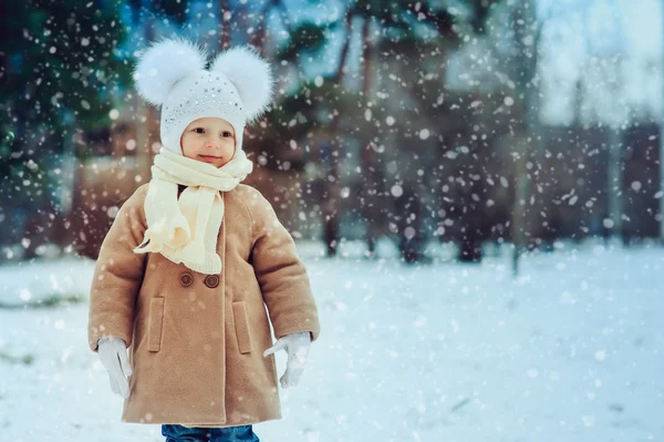 Carina bambina godendo di passeggiata invernale nel parco innevato, indossando cappello caldo e cappotto — Foto Stock