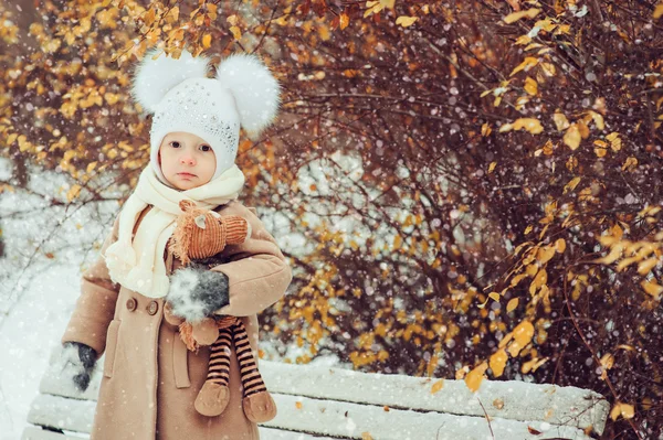 Aranyos baba lány élvezi téli séta a havas park, meleg kalapot és kabátot visel — Stock Fotó