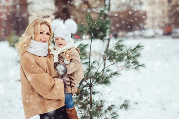 Happy mother and baby daughter walking in snowy winter park. Christmas family time. — Stock Photo, Image