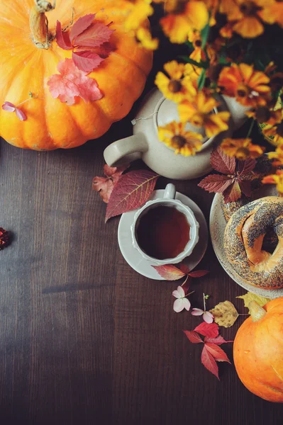 Vista superior del acogedor desayuno de otoño en la mesa en la casa de campo. Té caliente, calabazas, rosquillas y flores . —  Fotos de Stock