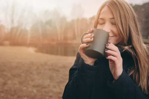 Soñadora joven bebiendo té caliente al aire libre en el paseo, disfrutando de viajar en el fin de semana de otoño — Foto de Stock