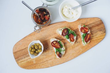 İtalyan geleneksel bruschetta - güneşte kurutulmuş domatesli ekmek tostu, krem peynir, zeytinyağı ve roka. 