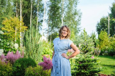 Bahçıvan kadın özel bahçede bir buket astilbe çiçeğiyle poz veriyor. Kır yaşamı ve peyzaj tasarımı kavramı