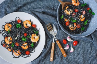 Karides, sarımsak ve tavada servis edilen kiraz domatesli siyah spagetti makarnası. Öğle yemeğinde nefis İtalyan yemeği.