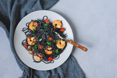 Tabakta servis edilen kiraz domatesli ve karidesli siyah spagetti makarnası. Lezzetli vejetaryen İtalyan yemekleri