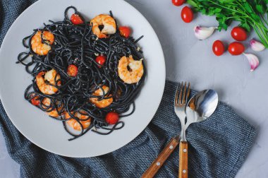 Tabakta servis edilen kiraz domatesli ve karidesli siyah spagetti makarnası. Lezzetli vejetaryen İtalyan yemekleri