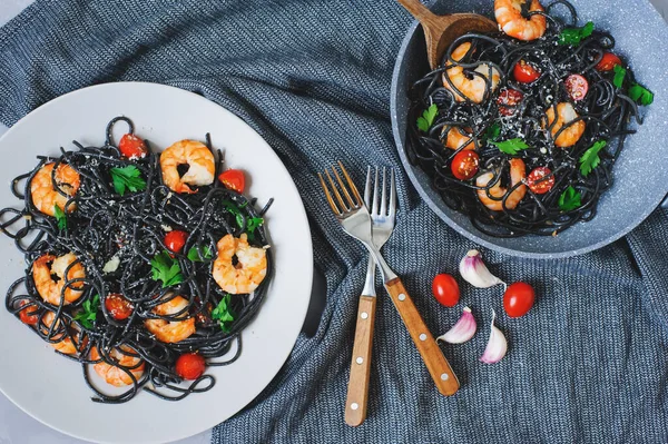 Karides, sarımsak ve tavada servis edilen kiraz domatesli siyah spagetti makarnası. Öğle yemeğinde nefis İtalyan yemeği.