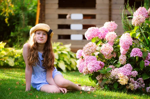 정원을 소녀가 분홍색하이 드란게아 매크로 근처에 포즈를 취하고 스톡 이미지