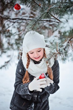 Gri ceket ve beyaz şapka, eşarp ve eldiven kız şirin çocuk oyuncak şakrak kuşu karlı kış orman içinde çalış