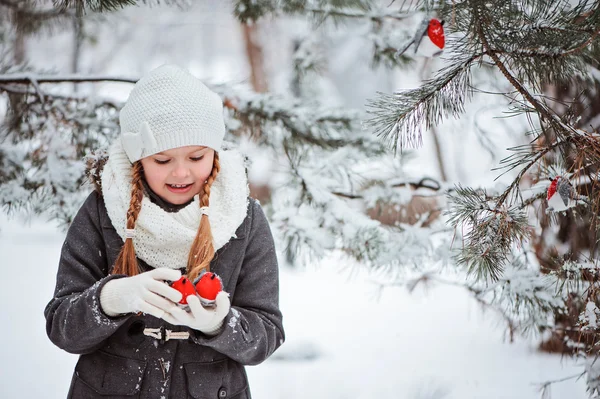 Gri ceket ve beyaz şapka, eşarp ve eldiven kız şirin çocuk oyuncak şakrak kuşu karlı kış orman içinde çalış