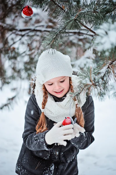 Gri ceket ve beyaz şapka, eşarp ve eldiven kız şirin çocuk oyuncak şakrak kuşu karlı kış orman içinde çalış