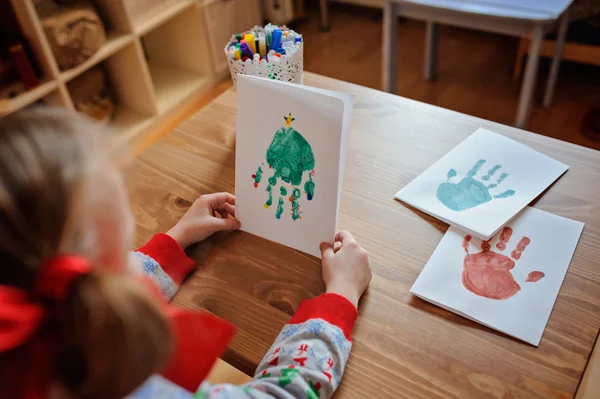 Child girl in knitted seasonal sweater  making christmas handprints post cards — Stock Photo, Image