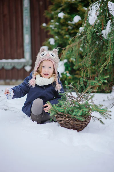 Cute happy child girl in owl hat and blue coat walking in winter snowy garden — Stock Photo, Image