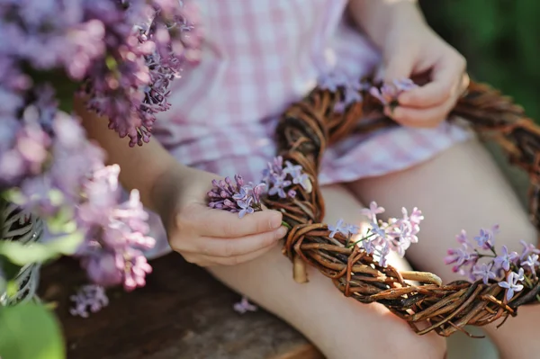 Child girl hands holding lilac wreath in spring garden — Stock Photo, Image