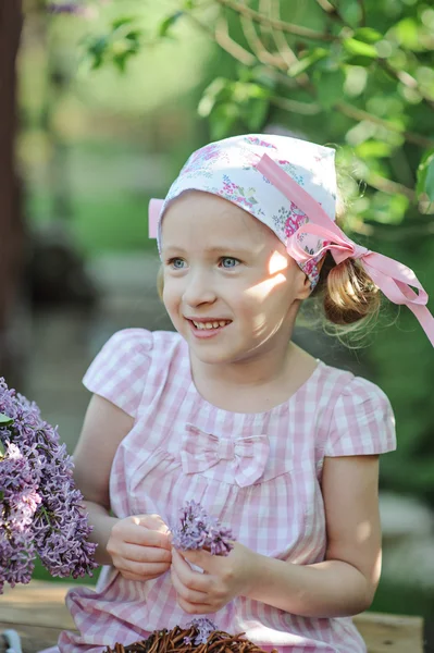 Cute happy child girl in flower headband portrait with lilacs in spring garden — Stock Photo, Image