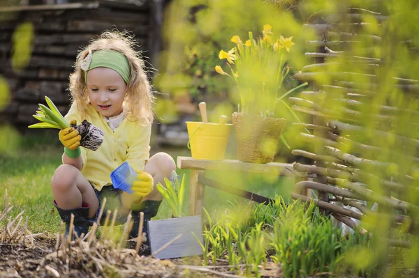 Linda niña feliz en cárdigan amarillo juega poco jardinero en el jardín de primavera — Foto de Stock