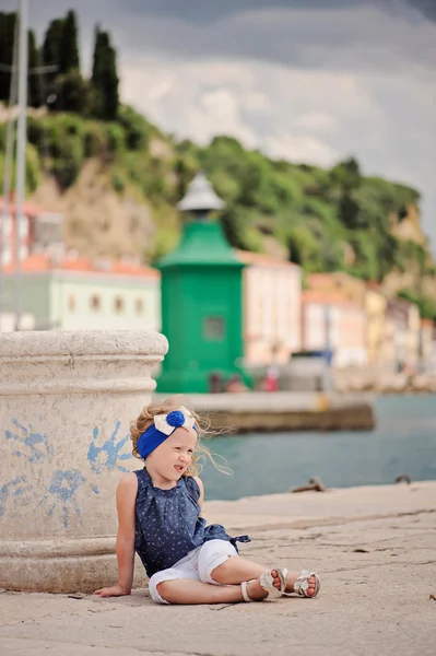 Linda niña rubia rizada en traje marino caminando en muelles en Piran, Eslovenia en el día de verano — Foto de Stock