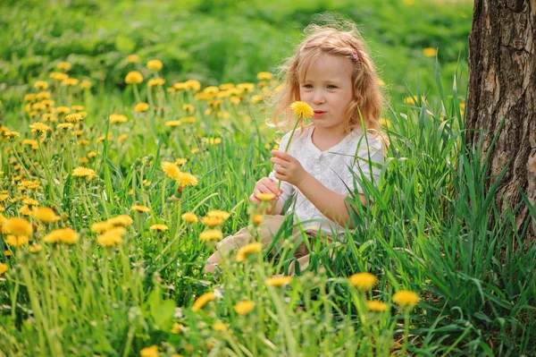 Linda niña rubia divirtiéndose en el campo de primavera dangelion — Foto de Stock