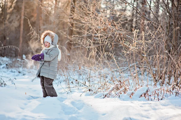 Cute child girl holding snow on the walk in winter snowy sunny forest — Stock Photo, Image