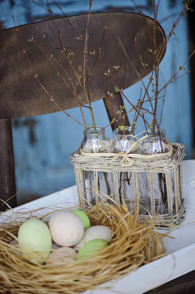 Œufs de Pâques dans le nid avec premières branches de printemps dans un panier vintage sur une table en bois — Photo