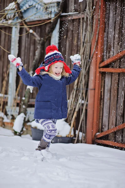 Cute happy child in christmas hat girl throwing snow and having fun in winter snowy garden — Stock Photo, Image