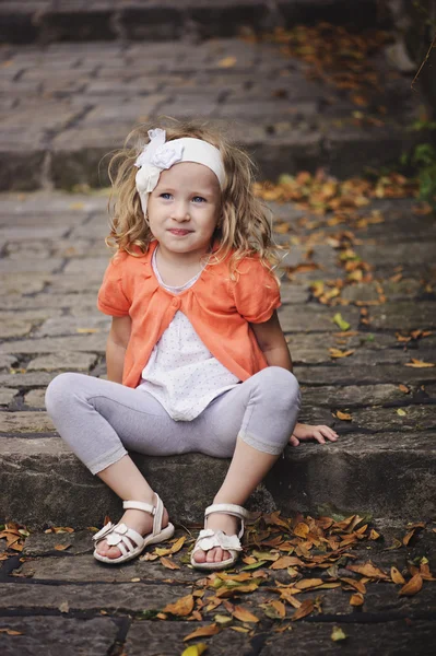 Cute child girl in orange cardigan playing at old stone road with stairs — Stock Photo, Image