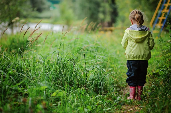 Bambino ragazza in stivali di gomma rosa e giacca leggera camminare sul lato fiume estate — Foto Stock