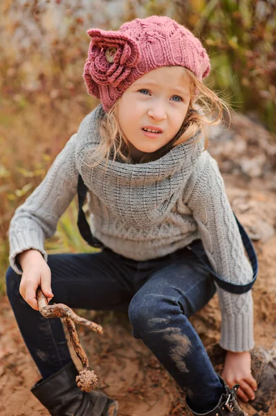 Linda niña en rosa sombrero de punto vertical retrato en el lado del río otoño con playa de arena —  Fotos de Stock