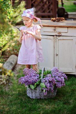 Bahar bahçesinde leylak vintage ahşap büro yakınındaki sepet bulunan kız şirin çocuk