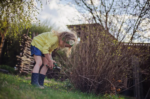 Gyermek lány vágás fa ágai tavasszal, és segít a kertben — Stock Fotó