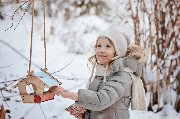 儿童女孩喂鸟在冬天花园 — 图库照片