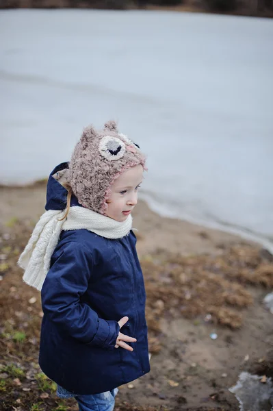 Söta barn flicka i blå rock och Uggla hatt på promenad på frusen sjö — Stockfoto