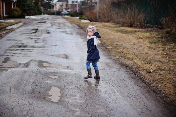 Cute toddler girl in blue coat and owl hat walking on the road in cold day — Stock Photo, Image