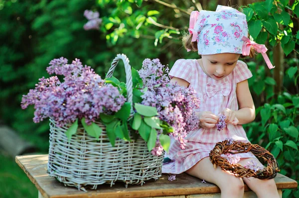 Dítě dívka dělat Lila věnec jarní zahradě — Stock fotografie