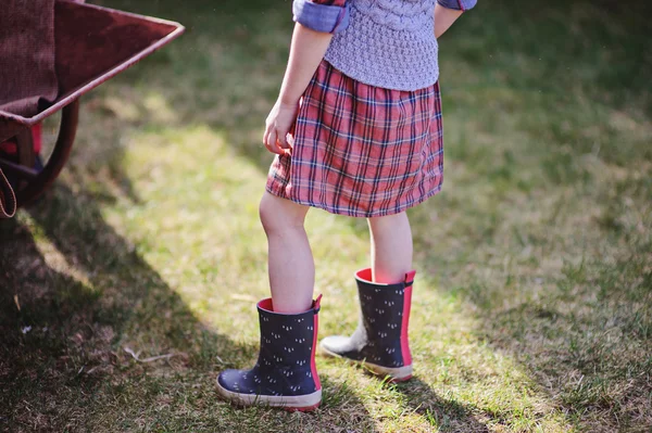 Child girl in rubber boots in spring garden — Stock Photo, Image