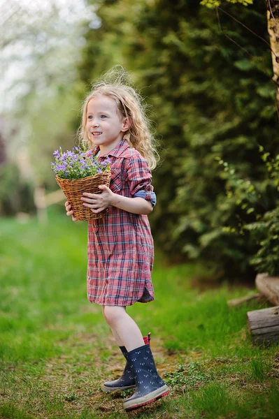 Dívka dítě baví v jarní zahradě s košíkem zvonků — Stock fotografie