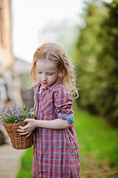 Spring portrait of cute curly child girl with basket of bluebell flowers — Stock Photo, Image