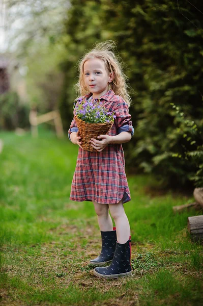 Dívka dítě baví v jarní zahradě s košíkem zvonků — Stock fotografie