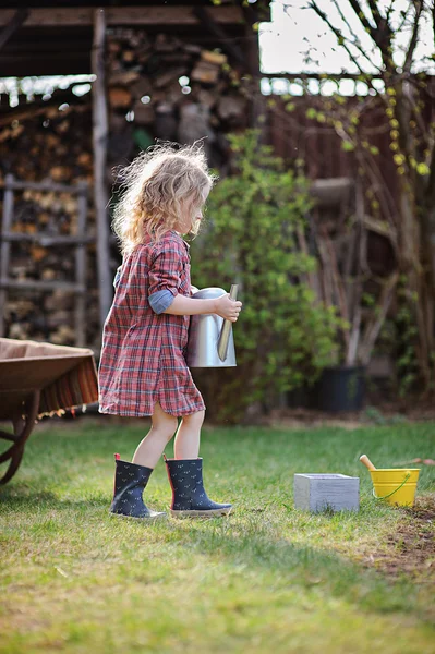 かわいい子春の庭の花の水やりじょうろを持つ少女 — ストック写真