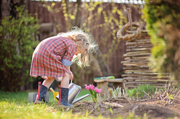 Schattig kind meisje drenken bloemen in lentetuin — Stockfoto