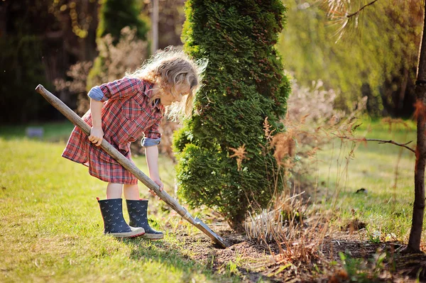 Linda niña ayuda en el jardín de primavera con pala — Foto de Stock