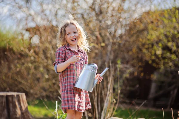 Счастливая девочка с консервной банку в весеннем саду — стоковое фото