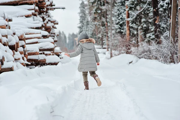 Mädchen läuft im schneebedeckten Wald spazieren — Stockfoto