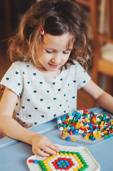 Linda niña preescolar juega con mosaicos en casa — Foto de Stock