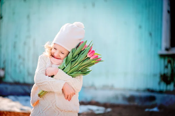 Очаровательная счастливая девочка с букетом тюльпанов на женский день на прогулке весной — стоковое фото