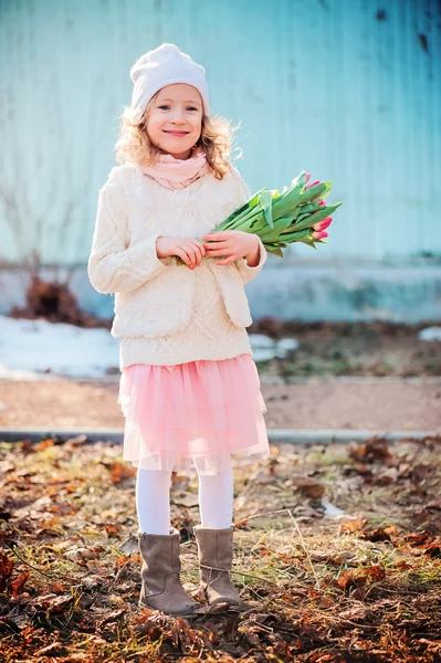 Adorable niña feliz con tulipanes ramo para el día de la mujer en el paseo en primavera — Foto de Stock